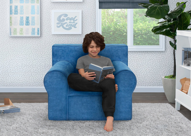 Child sitting in a blue armchair reading a book in a room with a window and plant. 10-XL Cozee Foam Chair - Perfect Size for Kids Ages 18 Months - 12 Years+