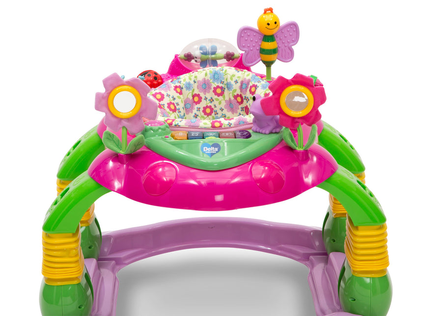 A colorful baby activity jumper toy with a pink and green frame, floral center panel, flower and bee hanging toys, and yellow-green support legs on a white background. 20-Lil’ Play Station 4-in-1 Activity Walker