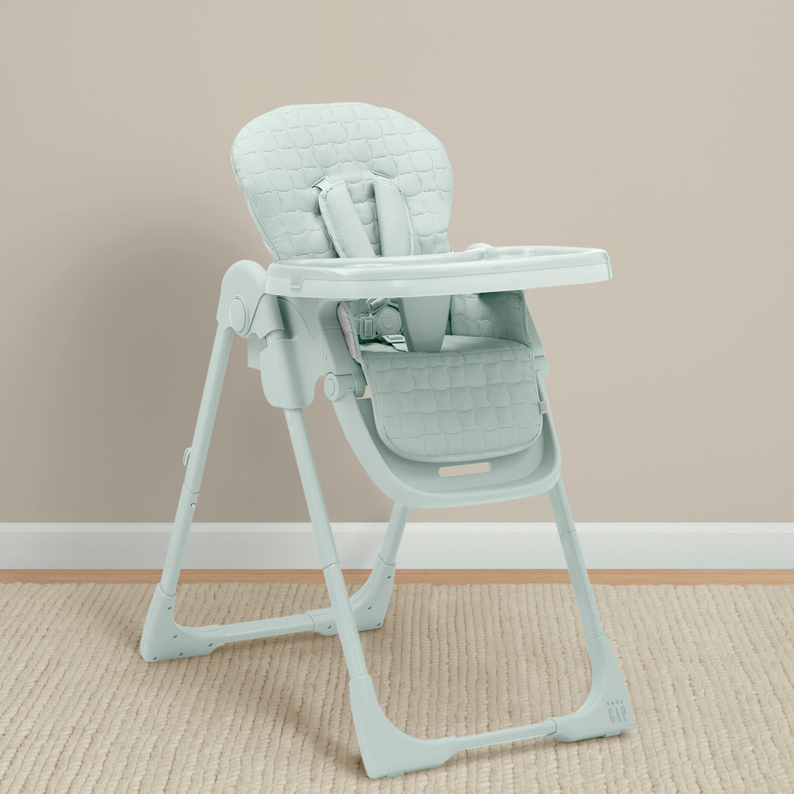 Light gray high chair on a beige carpet with a plain wall background