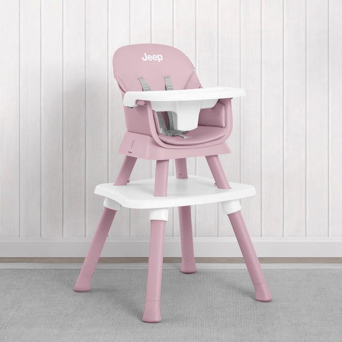A pink and white Jeep high chair with a matching tray table, set against a white wood-paneled wall and gray carpet. 42-Milestone 6-in-1 High Chair