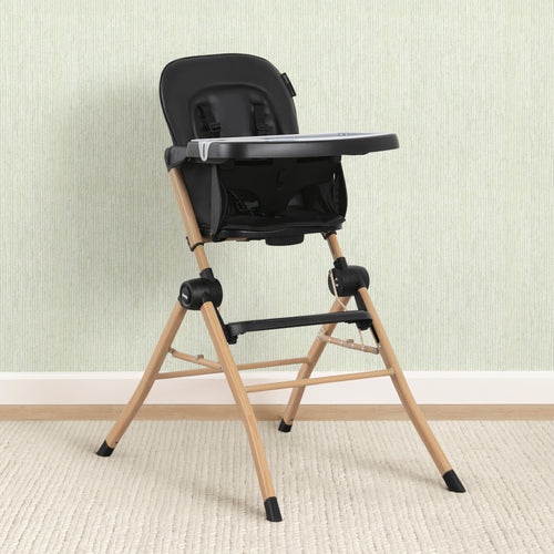 Black and beige high chair against a light-colored wall.
