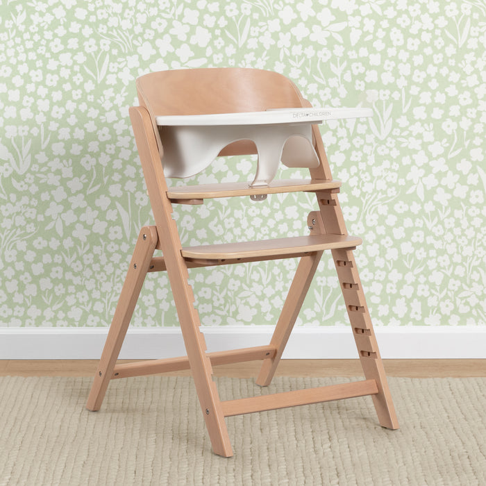 Wooden high chair against a floral wallpaper background 0-Crave 4-in-1 Convertible High Chair