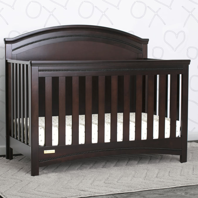 Dark wood crib in a room with a patterned wall. 24-Emma Crib 'N' More
