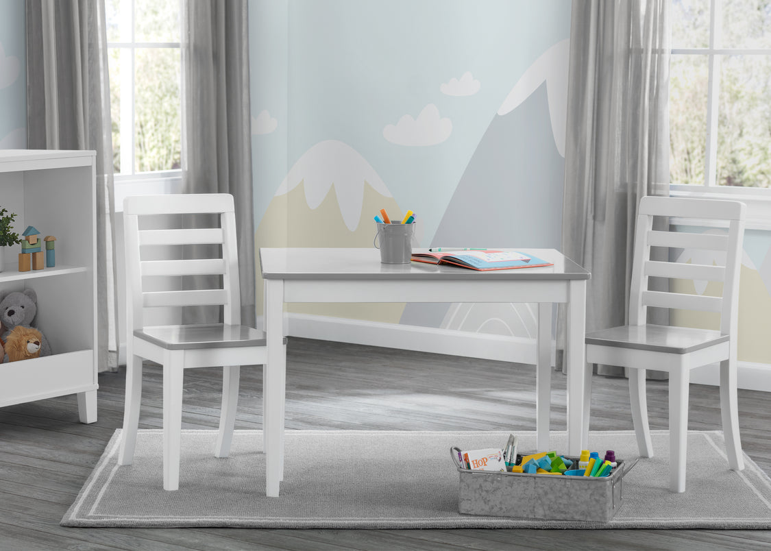 White children's table and chairs set in a room with toys and books.