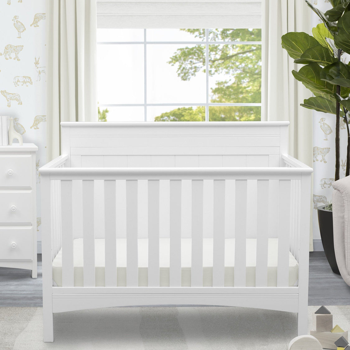 White crib in a room with a window and decorative elements