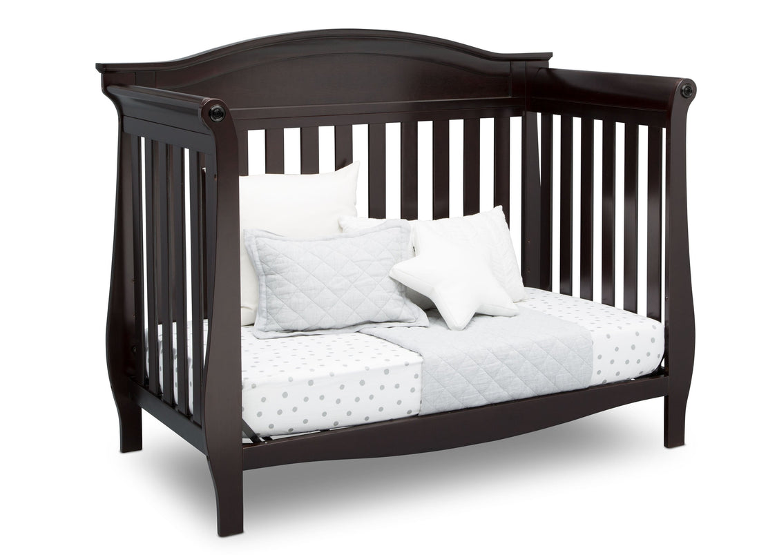 Dark wood crib with white bedding on a white background