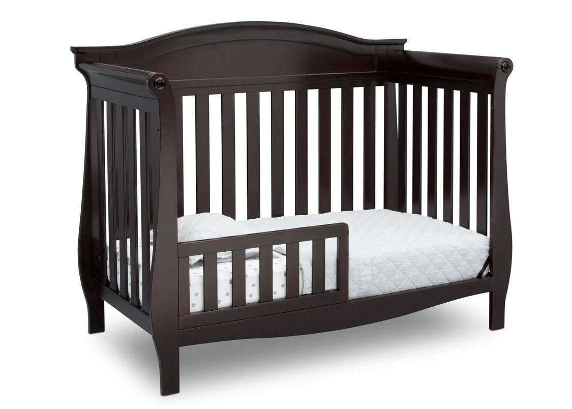 Dark wood crib with white mattress on a white background