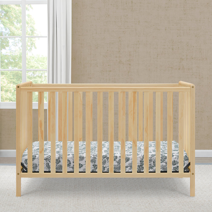 Wooden crib with a floral mattress cover in a room with a window and beige wall. 0-Heartland 4-in-1 Convertible Crib