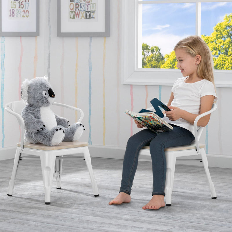 Child reading a book to a plush koala toy in a room with colorful wall art and a window.