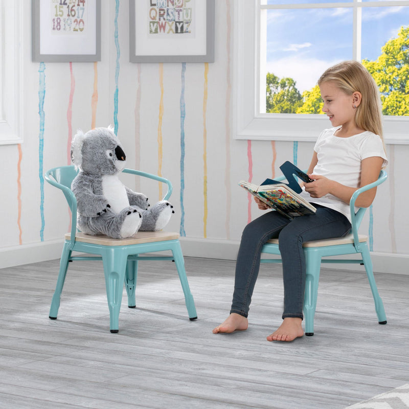 Child reading a book next to a stuffed koala toy in a room with striped wallpaper and a window.