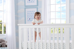 Baby standing in a crib 0