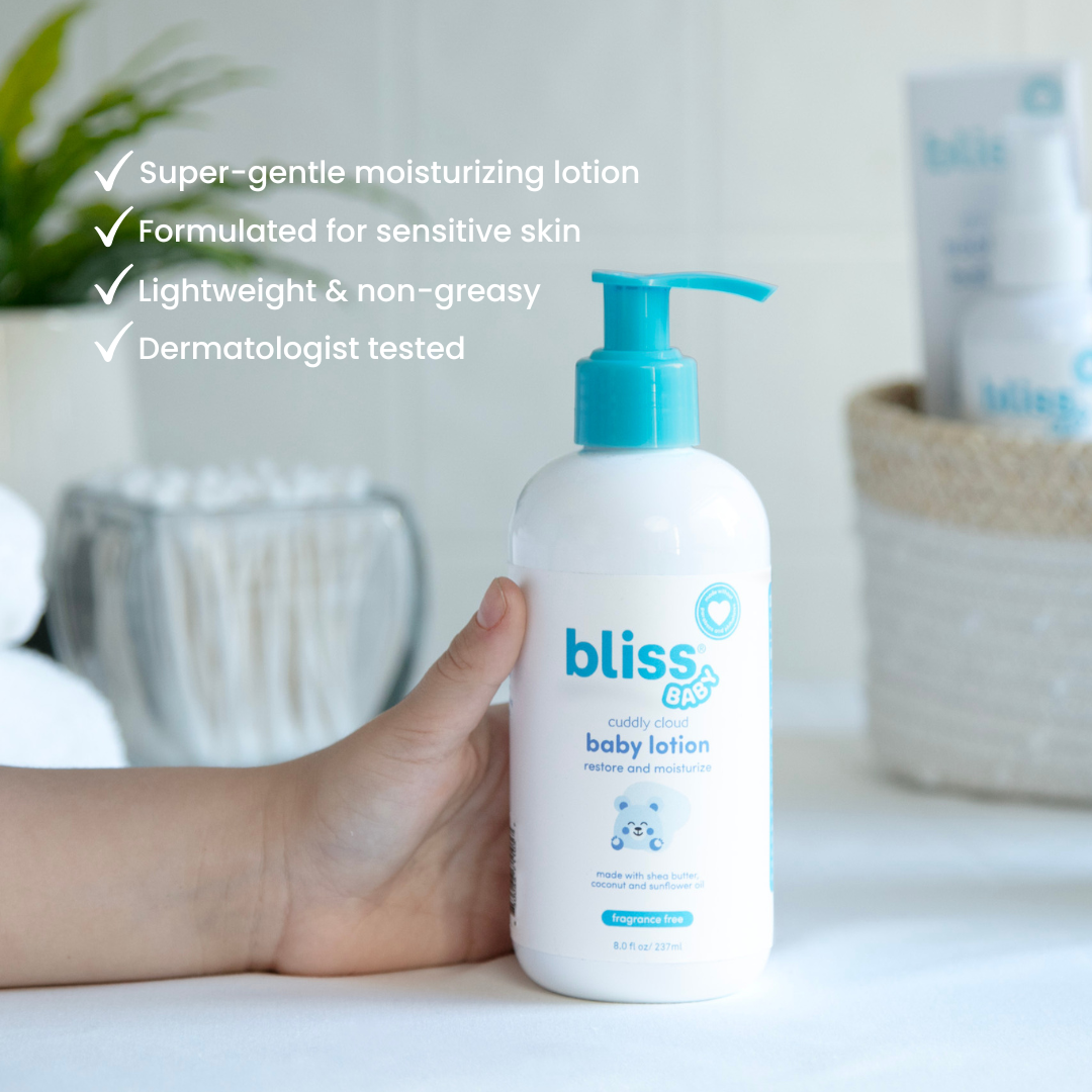 Bliss baby lotion bottle held by a hand with product details on a blurred background