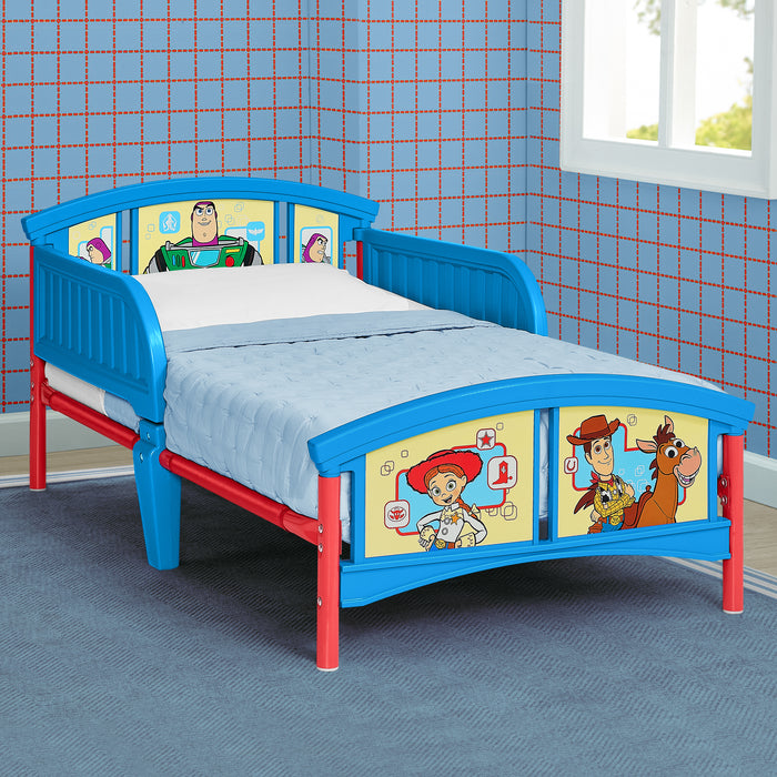 A children's bed frame in bright blue and red, featuring Woody and Buzz Lightyear character graphics on the headboard and footboard, shown in a room with blue grid-patterned wallpaper. 0-Toy Story 5 Plastic Toddler Bed