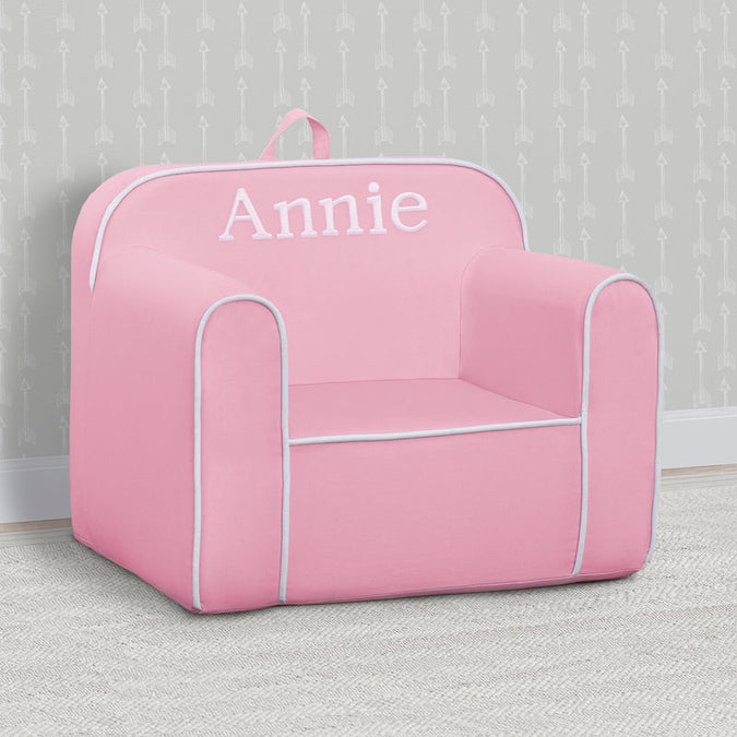 Pink children's chair with 'Annie' printed on it against a gray wall. 5-Personalized Cozee Chair for Kids