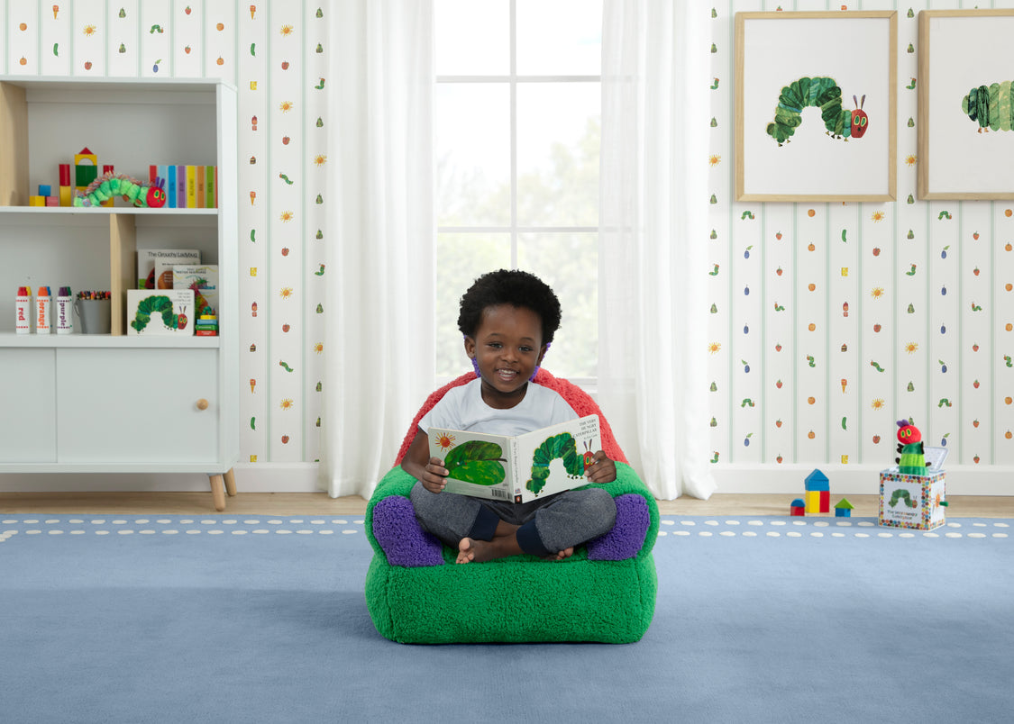 Child sitting on a green bean bag chair reading a book in a room with educational decor.