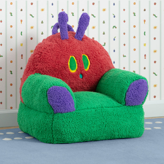 Children's chair designed like a cartoon caterpillar with red body, green wings, and purple antennas on a patterned floor. 0-World of Eric Carle, The Very Hungry Caterpillar Cozee Buddy Chair