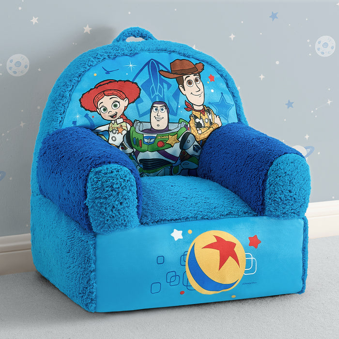 A plush children's armchair styled like a blue couch, featuring characters from Toy Story on the backrest and a large Ballpark graphic on the front, set against a light gray wall with white stars. 2-Toy Story Cozee Buddy Chair
