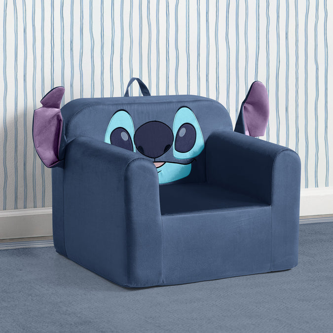 A blue plush children's armchair designed to look like a cartoon character face, with large light blue eyes, a dark nose, and purple ears, set against a striped wallpaper background. 8-Lilo & Stitch Cozee Kids Chair
