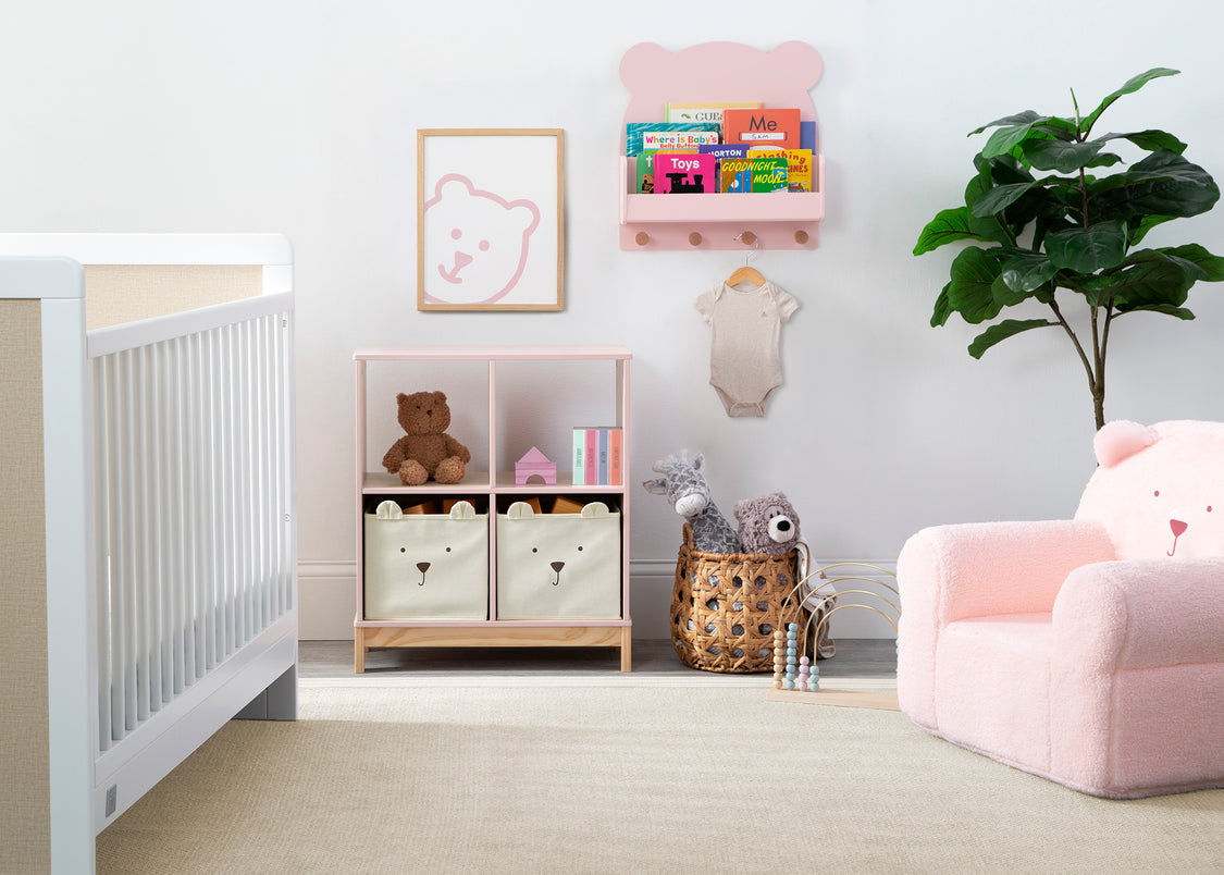Nursery room with white crib, storage unit, and pink chair.