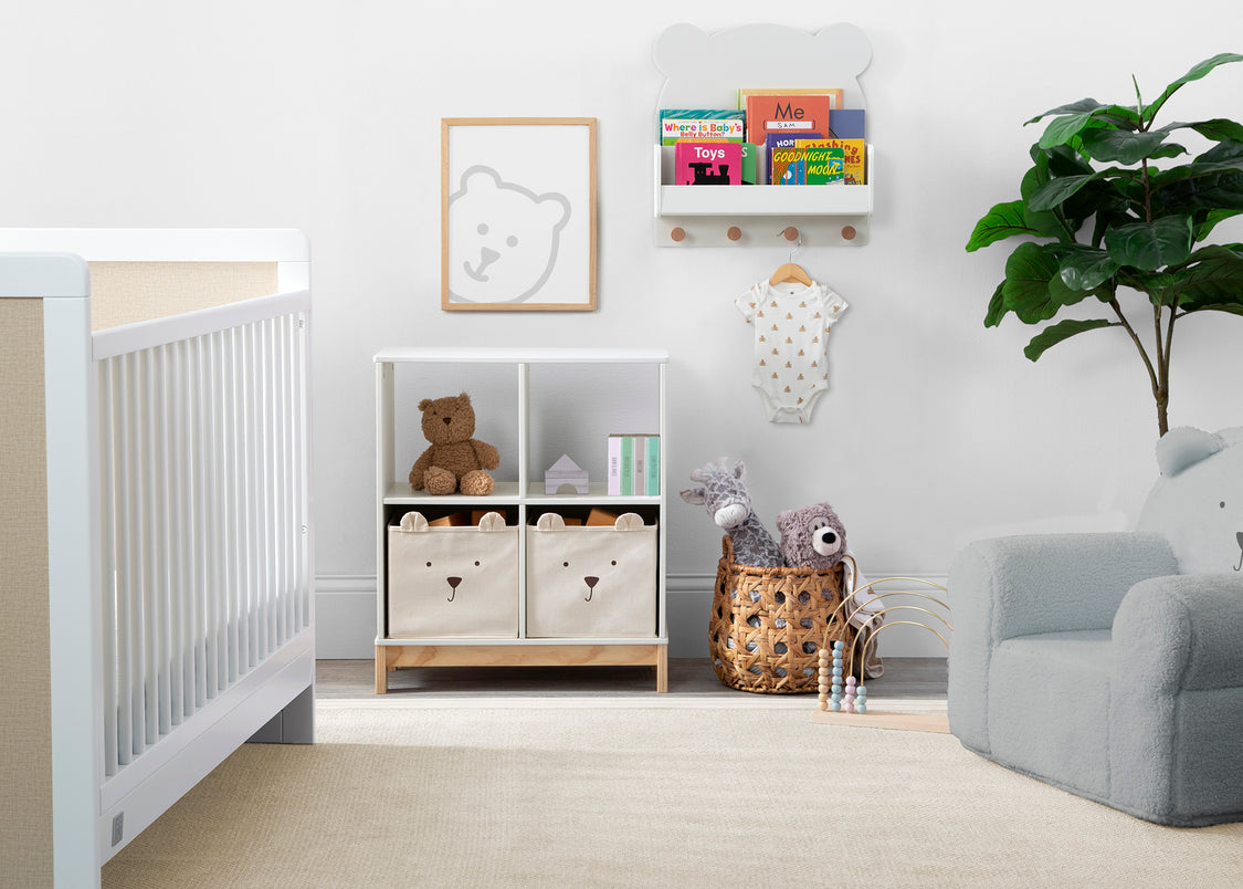 Nursery room with crib, bookshelf, and toys on a light wood floor.