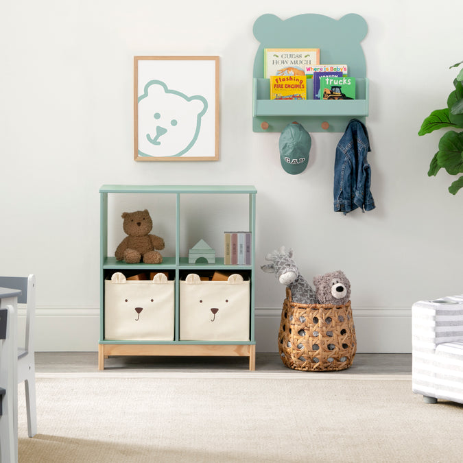 Children's room with storage cubes, teddy bear, and wall art in a light green color scheme. 28-Brannan Bear Bookcase with Bins