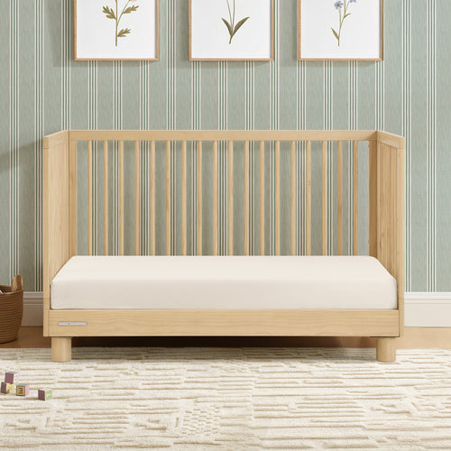 Wooden crib with white mattress against a striped wall