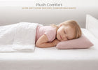 A young child sleeping peacefully on a white bed, resting on a soft blush pink pillow and covered with a white quilted blanket. The text at the top reads 'Plush Comfort' and 'ULTRA SOFT COVER FOR COZY, COMFORTABLE NIGHTS'. 20-Plush Comfort Toddler Pillow