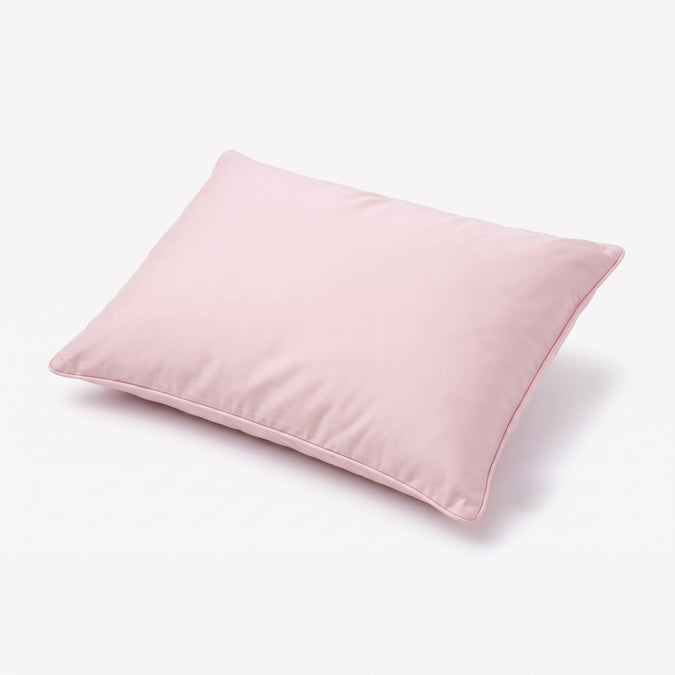 A light pink rectangular pillow with piped edges, shown at an angle on a clean white background. 27-Beautyrest Cooling Toddler Pillow