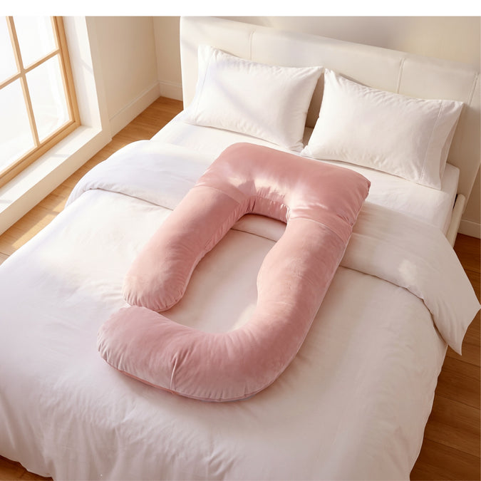 A pink U-shaped body pillow resting on a neatly made bed with white linens and pillows in a bright bedroom. 41-U-Shaped Pregnancy Pillow with Customizable Head Pillow