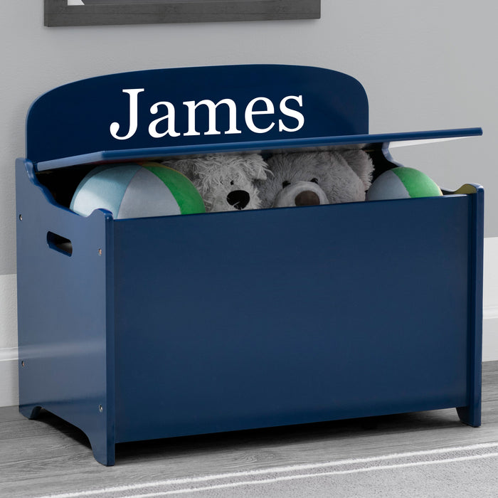 Navy blue toy storage box with 'James' on top, containing stuffed toys, against a gray wall. 1-Personalized MySize Deluxe Toy Box