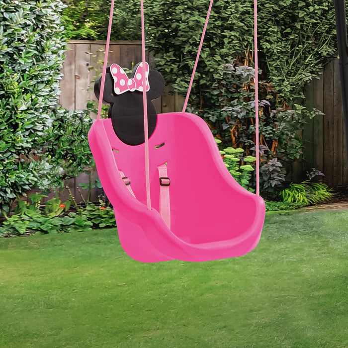 A pink outdoor kids' swing with Minnie Mouse decoration, featuring a safety harness, shown in a backyard setting. 1-Minnie Mouse 2-in-1 Outdoor Kids Swing