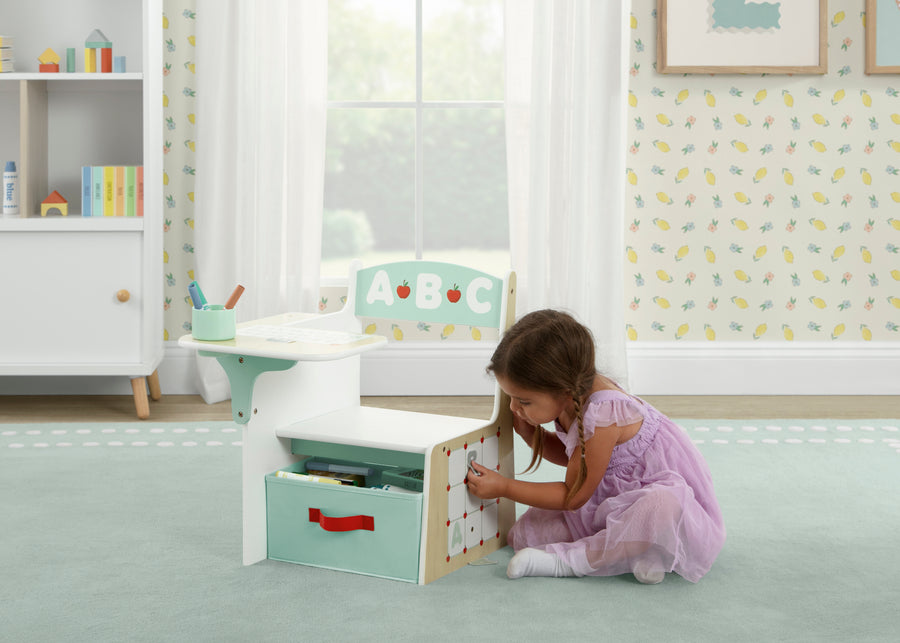 Child playing with a toy storage unit in a bright, child-friendly room. 7-ABC Alphabet Chair Desk with Storage Bin