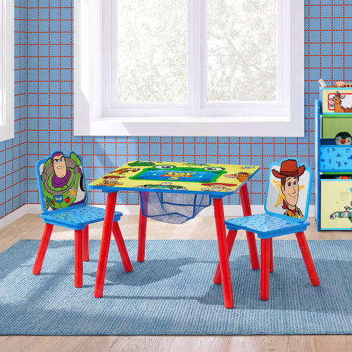 A children's table and chair set with a colorful cartoon print, styled in a kid's room with blue grid wallpaper, a window, and a blue rug. The set includes a square table and two chairs featuring Toy Story characters like Buzz Lightyear and Woody.