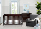 Nursery room with a crib, chair, and dresser. 9-Taylor 4-in-1 Convertible Crib