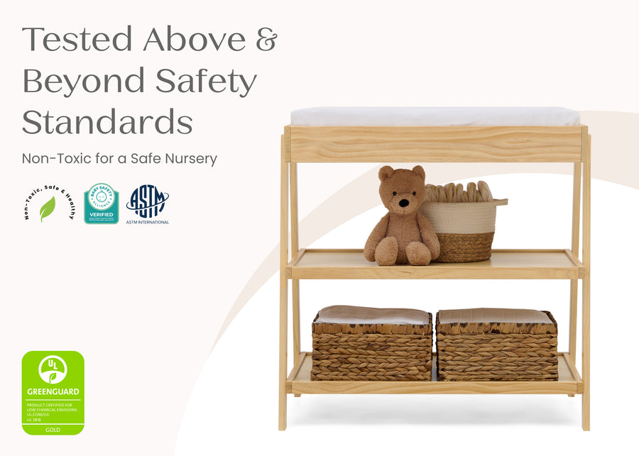 Wooden changing table with teddy bear and baskets on a white background, featuring safety certification logos. 72-Scout Changing Table