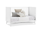 White crib with decorative pillows on a white background 12-Dylan 4-in-1 Convertible Crib