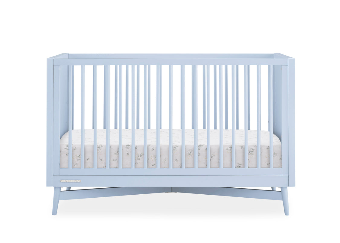 Light blue crib with white mattress on a white background