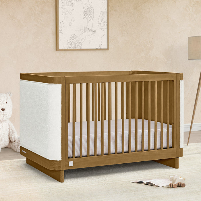 Wooden crib in a nursery with a teddy bear and lamp in the background 0-babyGap Callie 4-in-1 Upholstered Crib