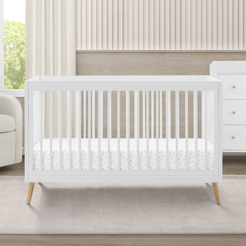 White crib in a nursery with a neutral color scheme