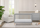 Gray crib in a nursery with a white armchair and dresser. 34-Jordan 4-in-1 Convertible Crib