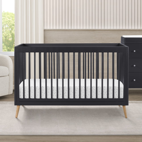 Black crib with white mattress in a nursery setting
