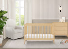 Nursery room with a wooden crib, white chair, and dresser. 48-Jordan 4-in-1 Convertible Crib