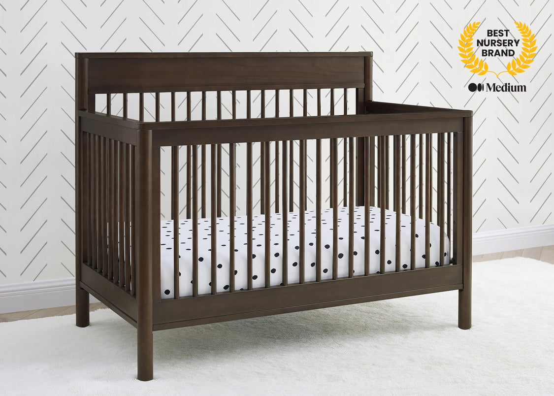 Wooden crib with white crib sheet against a white wall with a geometric pattern