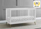 White crib with a polka dot mattress in a room with gray walls and a gray carpet. 18-Sloane 4-in-1 Acrylic Convertible Crib