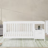White crib and changing table set in a nursery with a neutral color scheme. 34-Alice 5-in-1 Convertible Crib and Changer