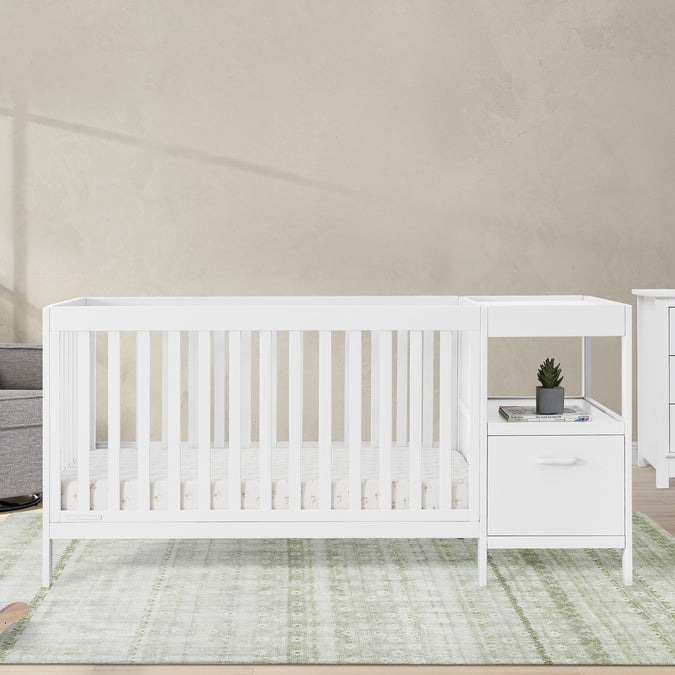 White crib and changing table set in a nursery with a neutral color scheme. 34-Alice 5-in-1 Convertible Crib and Changer