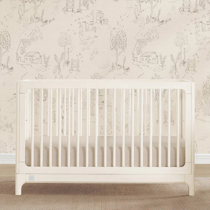 White crib in a room with decorative wallpaper featuring small illustrations of houses and trees. 2-babyGap Wren Collection