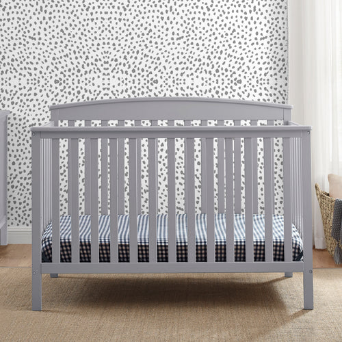 Gray crib with checkered bedding against a patterned wall