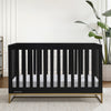 Black crib in a room with 'River Grace' wall art and plants. 33-Jade 4-in-1 Convertible Crib
