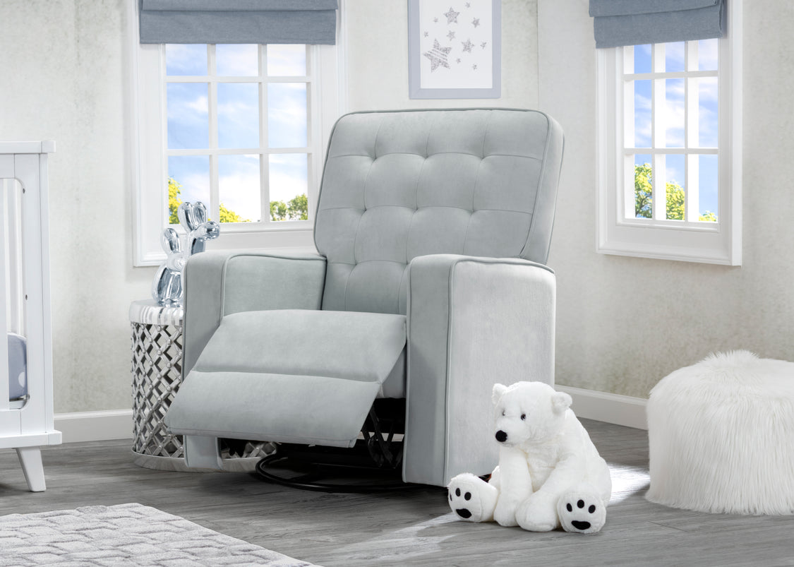 Gray recliner chair in a nursery with a teddy bear and crib.
